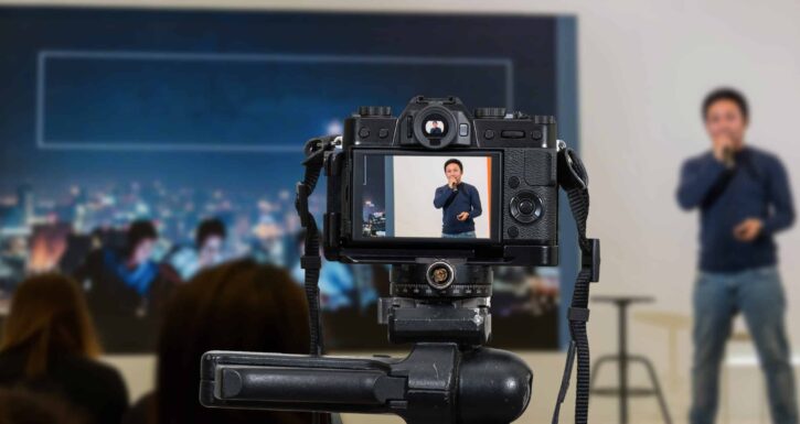 Professional digital Mirrorless camera with microphone on the tripod recording video blog of asian Speaker on the stage seminar, Camera for photographer or Video and Technology Live Streaming concept