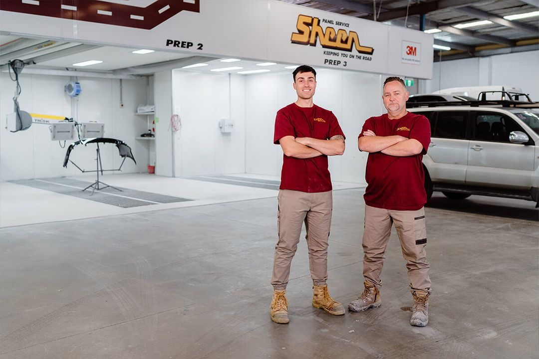 Location Landing Pages: 6 Crucial Elements Of Local Visibility | The Sheen Panel Services team is wearing uniforms and is in the garage where they repair damaged vehicles.
